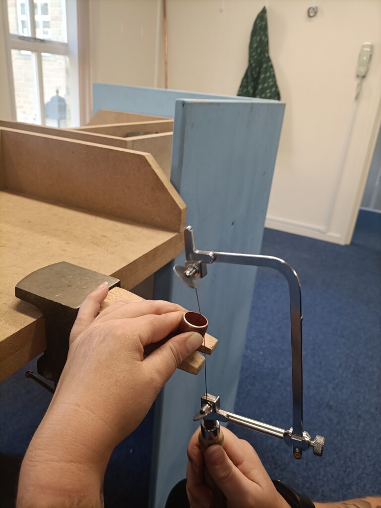 img20241007140451 Student's hand cuts a small piece of copper using a jewellery saw